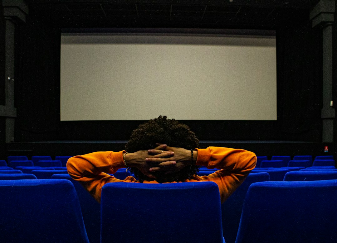 Person sitting alone in a movie theater in front of a glowing screen